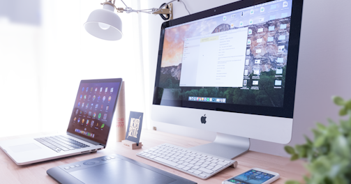 silver iMac near iPhone on brown wooden table