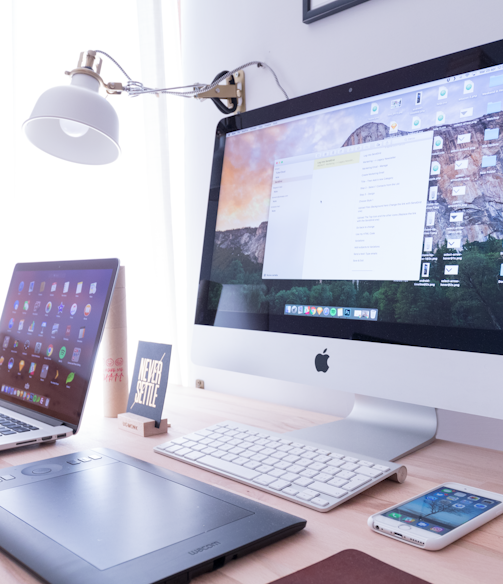 silver iMac near iPhone on brown wooden table