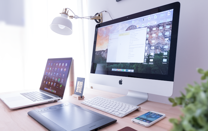 silver iMac near iPhone on brown wooden table