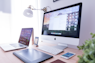 silver iMac near iPhone on brown wooden table