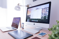 silver iMac near iPhone on brown wooden table