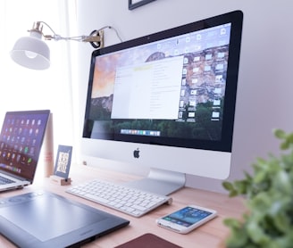 silver iMac near iPhone on brown wooden table