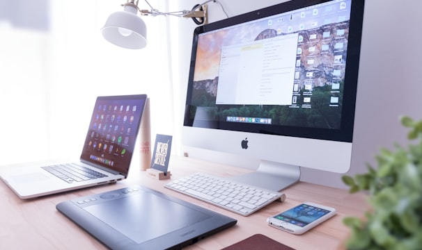 silver iMac near iPhone on brown wooden table