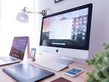 silver iMac near iPhone on brown wooden table