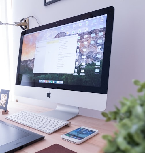 silver iMac near iPhone on brown wooden table