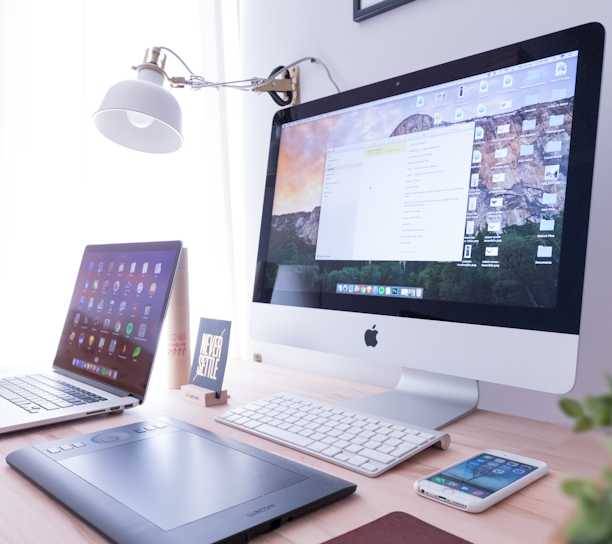 silver iMac near iPhone on brown wooden table