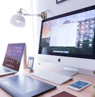 silver iMac near iPhone on brown wooden table