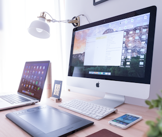 silver iMac near iPhone on brown wooden table