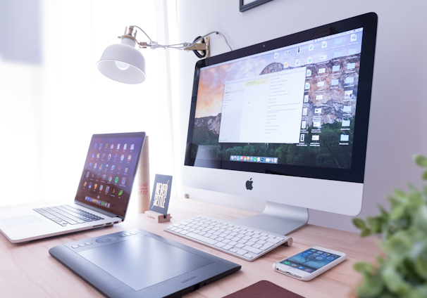 silver iMac near iPhone on brown wooden table