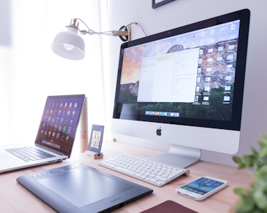 silver iMac near iPhone on brown wooden table