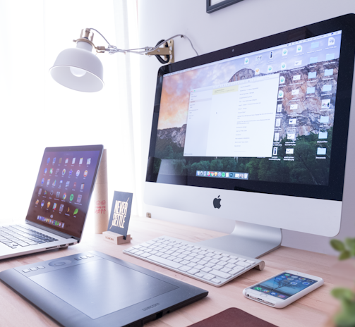 silver iMac near iPhone on brown wooden table