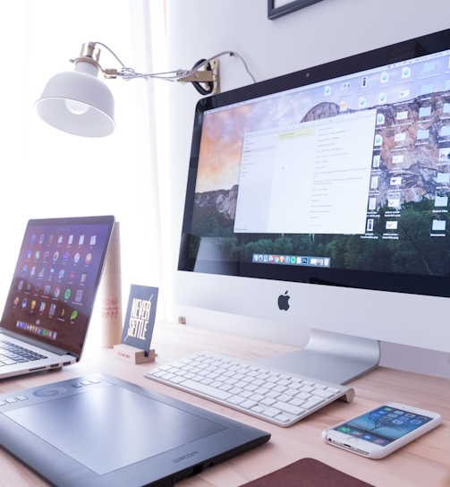 silver iMac near iPhone on brown wooden table