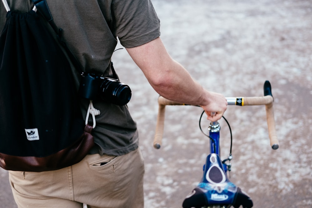 日中に屋外を歩きながら茶色と青の自転車�を持つ男性