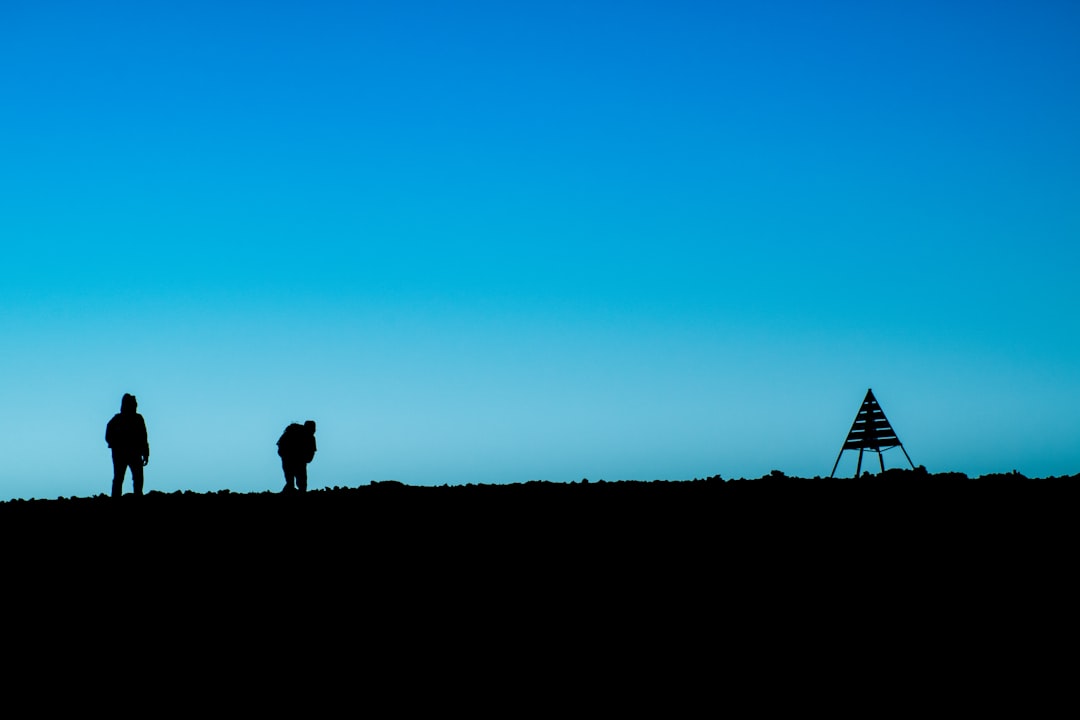silhouette of two person standing on ground near tent at daytime