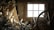 A wooden room filled with various antlers stacked against the wall and an old wooden wagon wheel in the right foreground. The light from the small window casts a warm glow on the objects, creating intricate shadows.