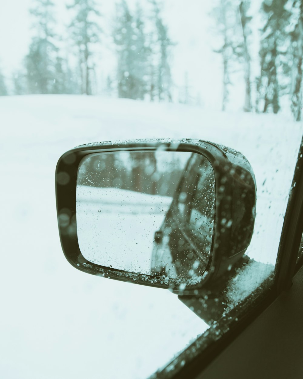 selective focus photography of left side mirror of vehicle on snow field