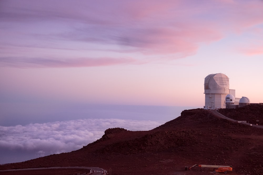 white concrete tower on peak near white clouds