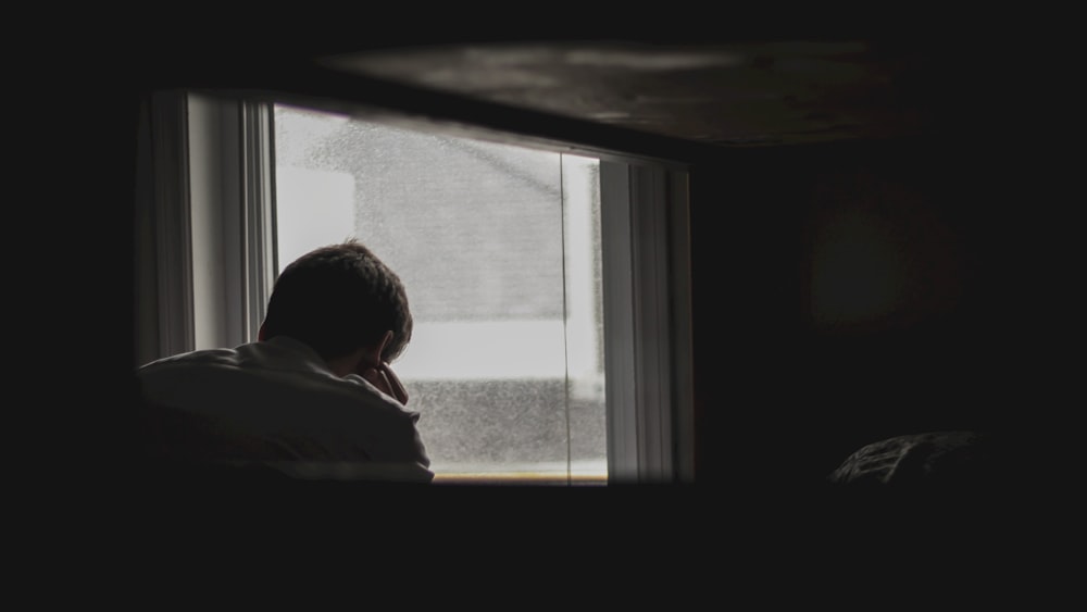 man looking outside by window