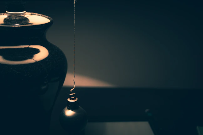 Close-up of a delicate gold-accented handmade ceramic vase on soft cream textured paper.