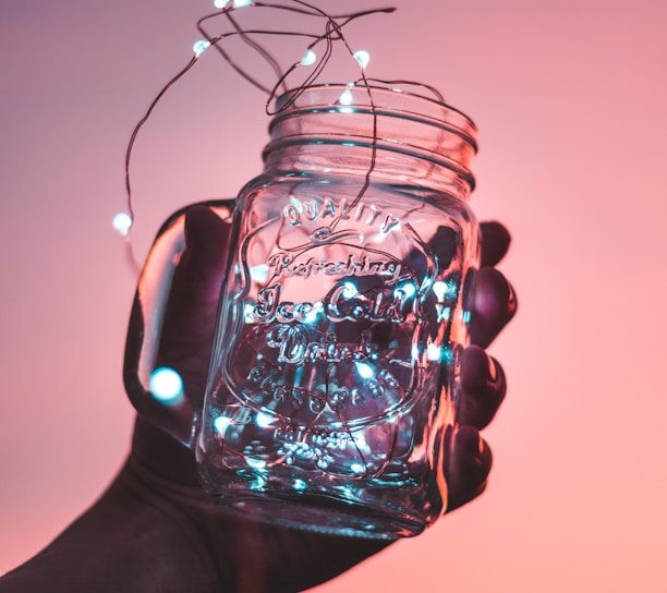 person holding clear glass mason jar with strip lights inside