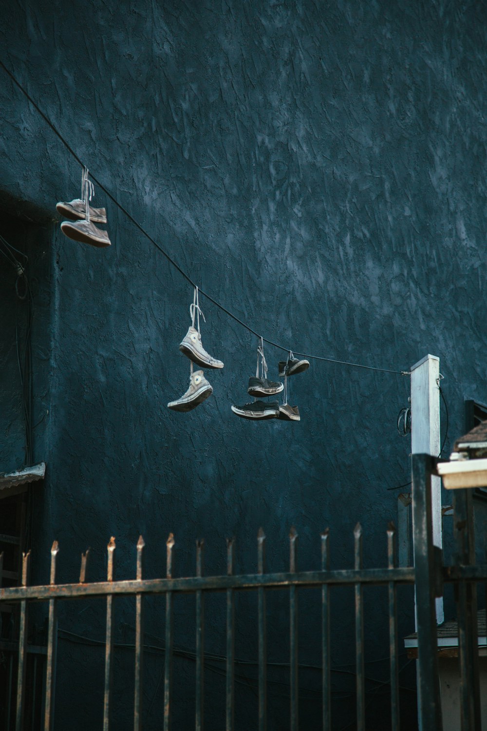 shoes hanged on black wire near metal gate