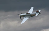 The L39 Albatros performing a sharp banking turn with a backdrop of dark clouds.