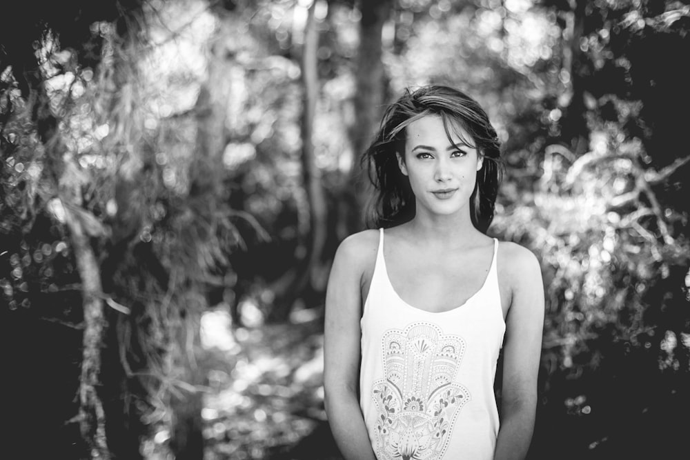 grayscale photography of woman standing front of forest