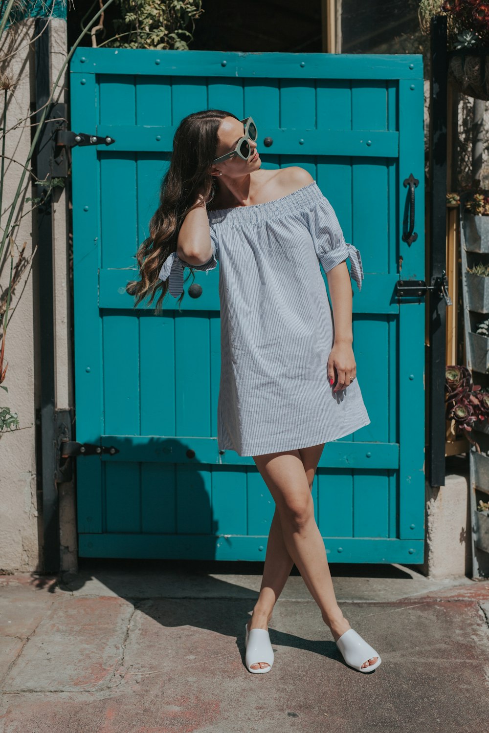 woman touching her hair standing near teal gate