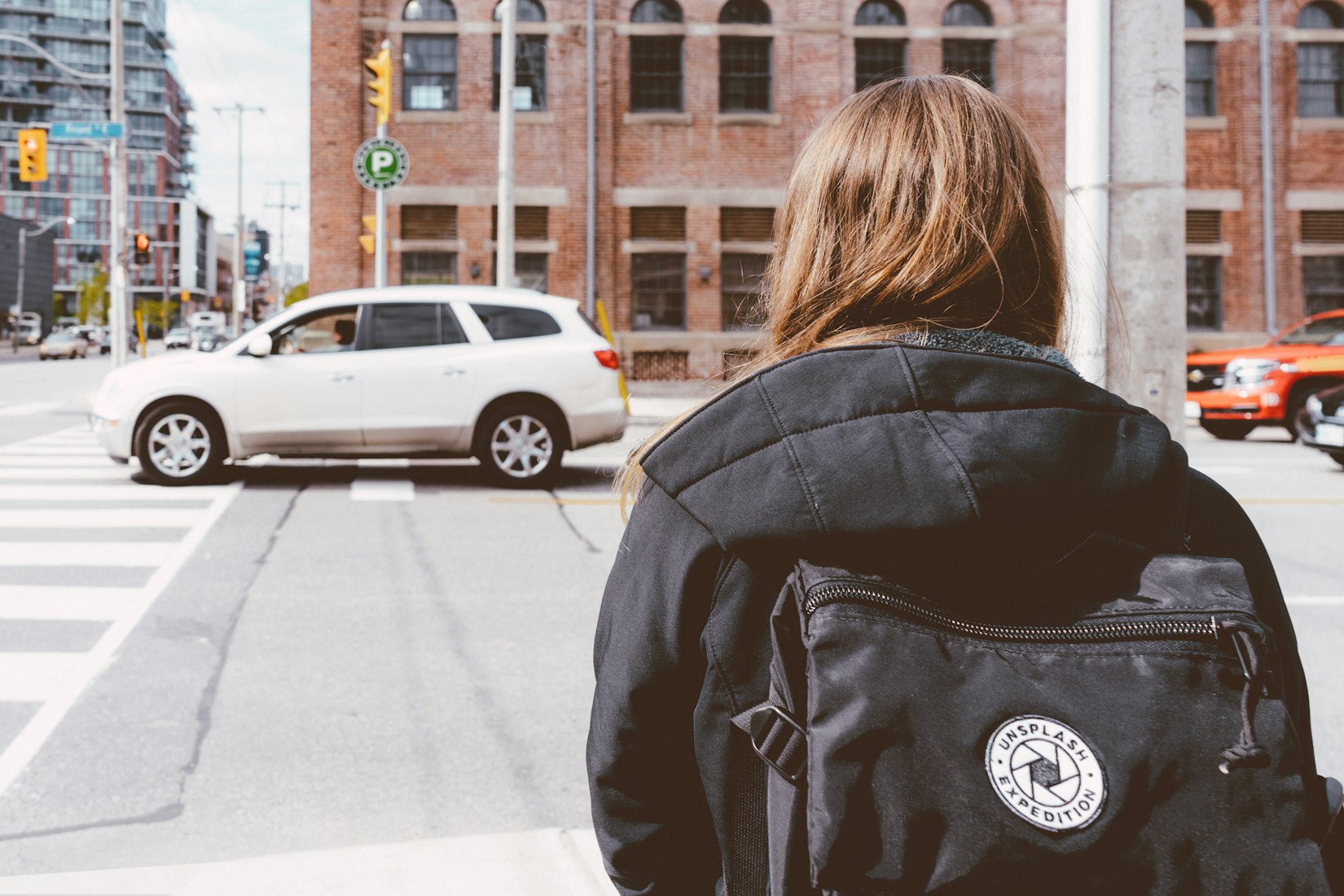 A woman with a black backpack waiting to cross the street in Toronto
