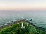 aerial photography of white tower on island near sea under white clouds