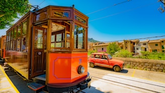 Soller train in Mallorca passing through rails beside red vehicle