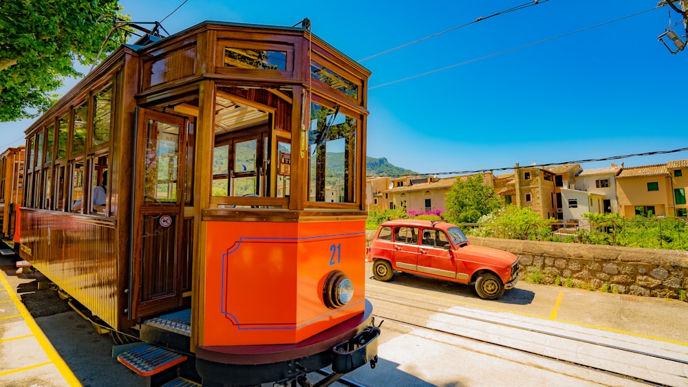 Tren rojo que pasa a través de rieles al lado del vehículo rojo