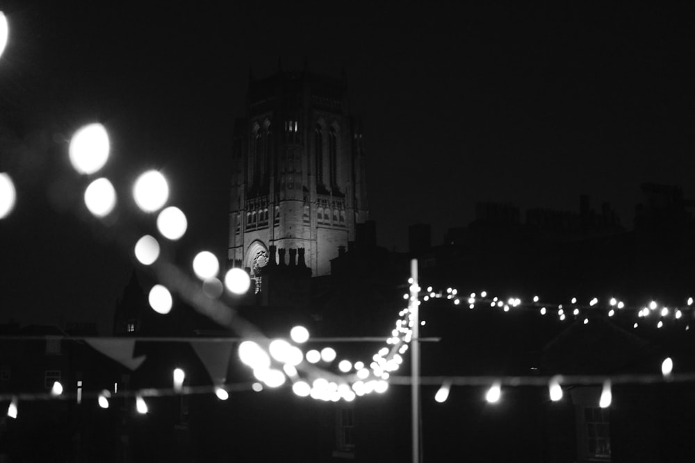 grayscale photography of stringlights and tower