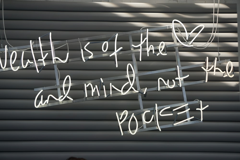 White paint on a garage door that says "Wealth is of the heart and mind not the pocket."