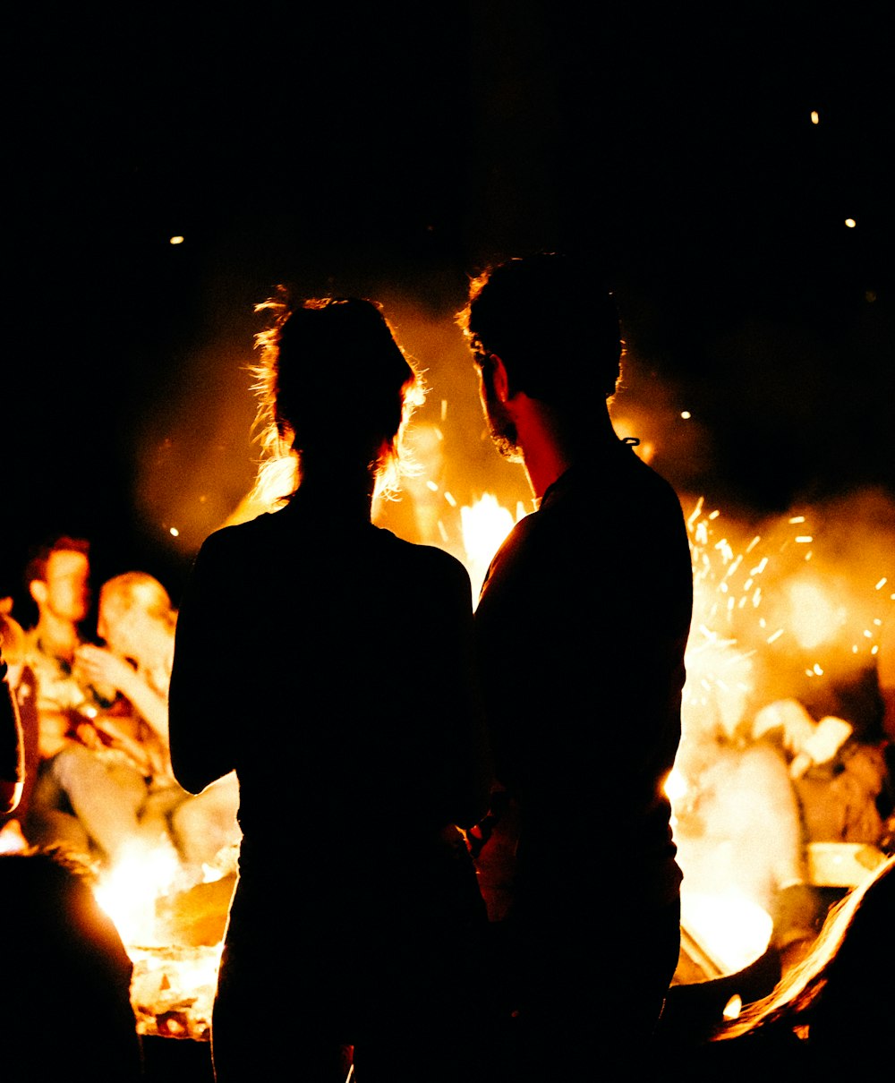 two persons standing in front of bonfire