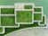 Aerial view of a geometric arrangement of green grass and concrete paths. A person wearing a yellow shirt lies at the center, providing a focal point within the structured landscape design.