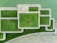 Aerial view of a geometric arrangement of green grass and concrete paths. A person wearing a yellow shirt lies at the center, providing a focal point within the structured landscape design.