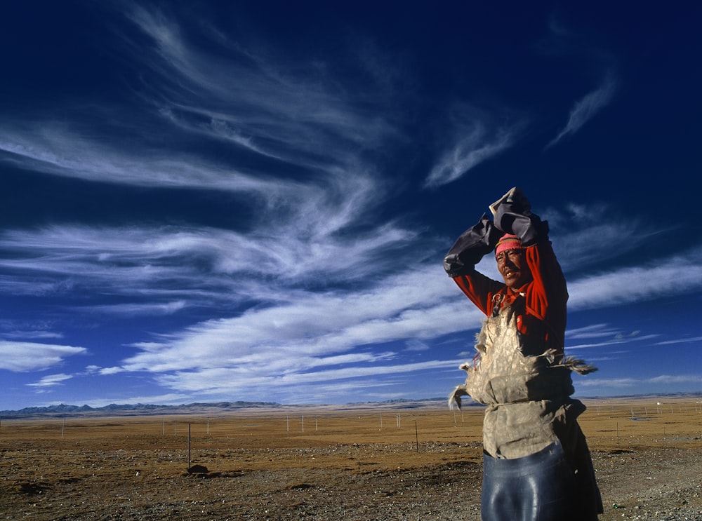 Hombre de pie cerca de la valla de acero gris bajo las nubes blancas durante el día