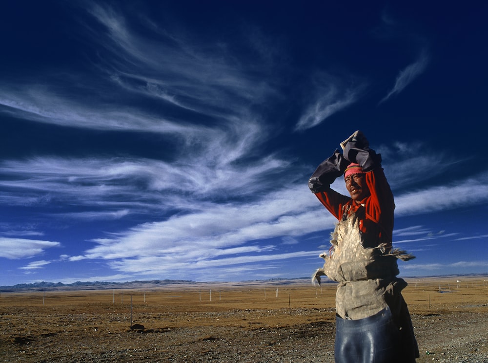 man standing near gray steel fence under white clouds during daytime