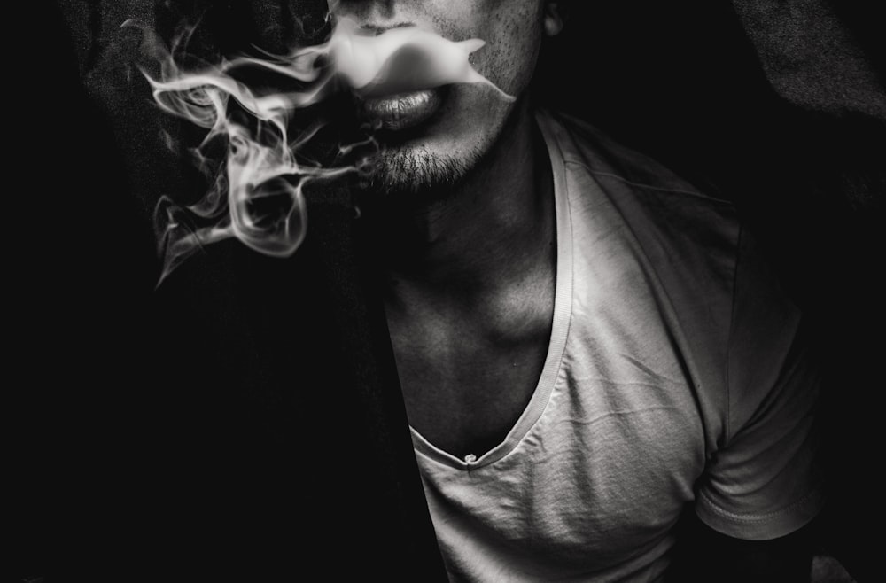 Mann trägt weißes Hemd mit V-Ausschnitt und Rauch kommt aus dem Mund