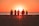 silhouette photo of five person walking on seashore during golden hour