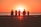 silhouette photo of five person walking on seashore during golden hour