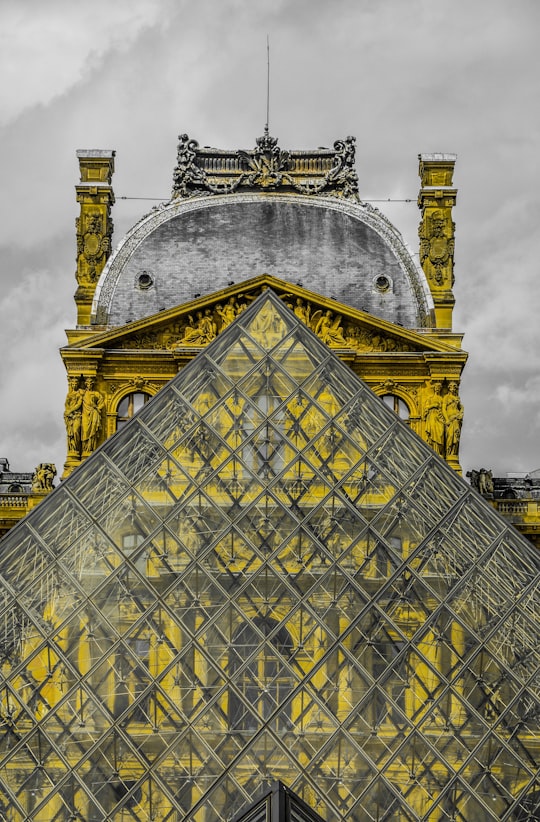 photo of glass triangle-shape building under nimbus cloud in Louvre France