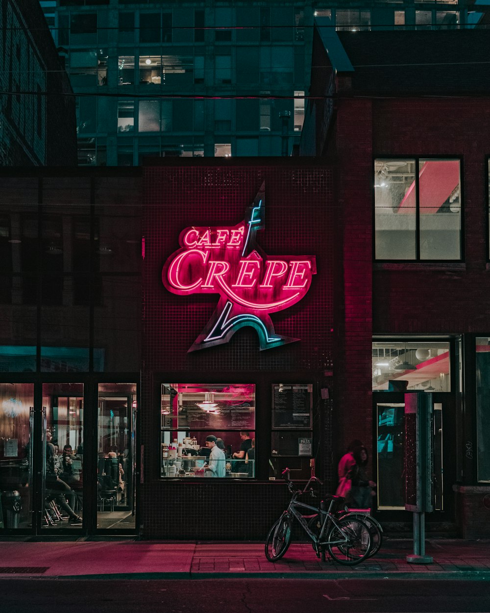 dos personas de pie frente a la tienda Cafe Crepe