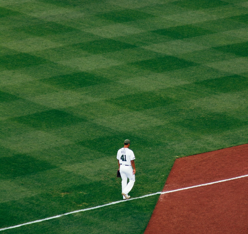 baseball player standing on field steps on white line at daytime