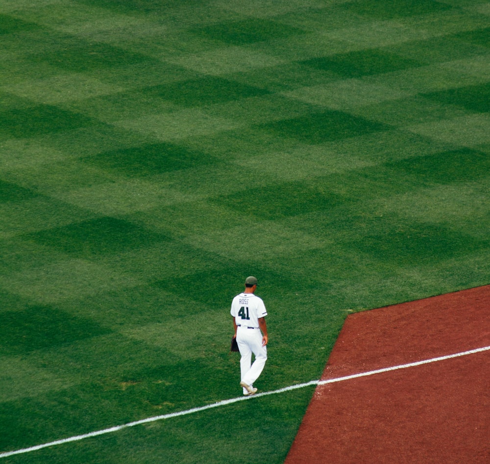 jogador de beisebol em pé nos degraus do campo na linha branca durante o dia