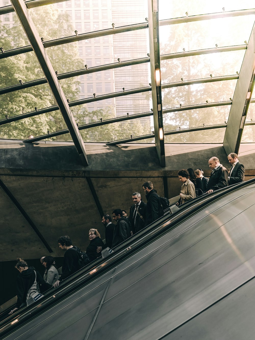 A line of people in business attire on an escalator in Canary Wharf