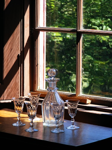 A rustic wooden table adorned with colorful glassware catching natural light.
