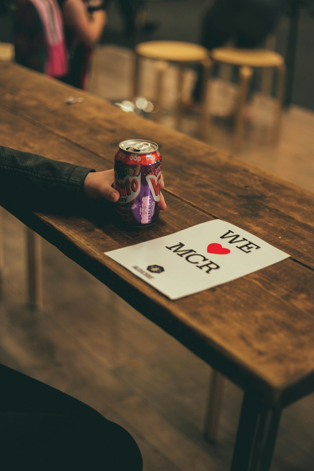 A person holding a canned beverage next to a 