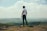 man standing on bolder overlooking the hills and mountains